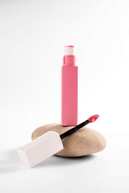 Pink liquid lipstick and applicator brush with open tube Makeup cosmetic product Bright background