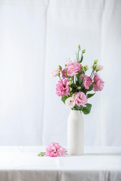 Pink lisianthus flowers in white vase