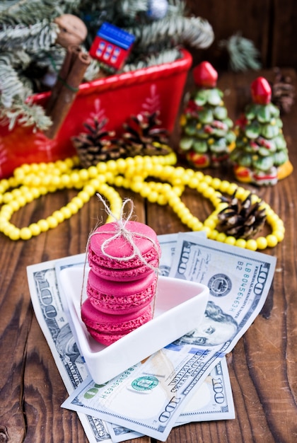 Pink macaroons and twenty euros with christmas decorations on woood