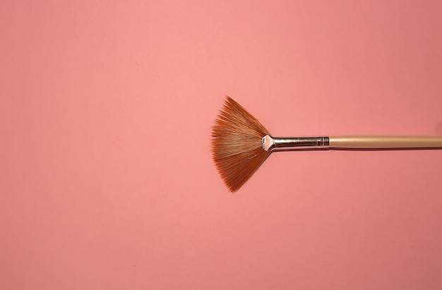 Photo pink make-up brush on pink background.