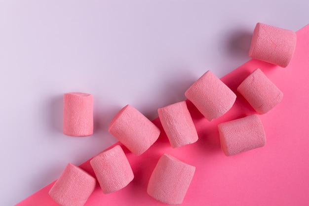 Pink marshmallow lies on white paper, copy space