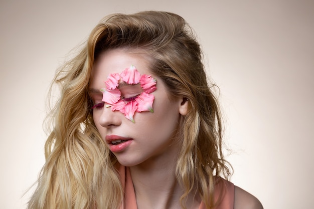 Pink mascara. Blonde-haired appealing young model with pink mascara closing eyes while posing