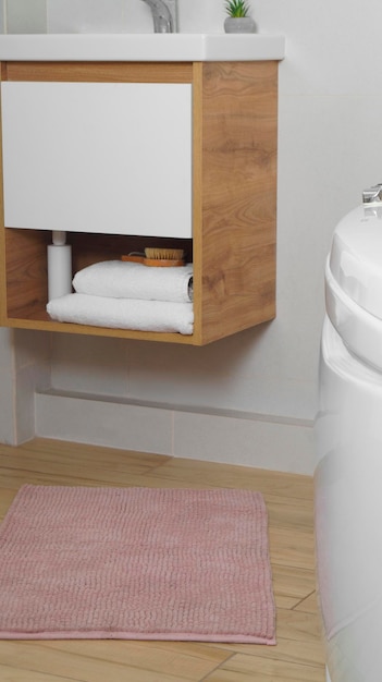 Pink mat near sink and tub on wooden floor in bathroom