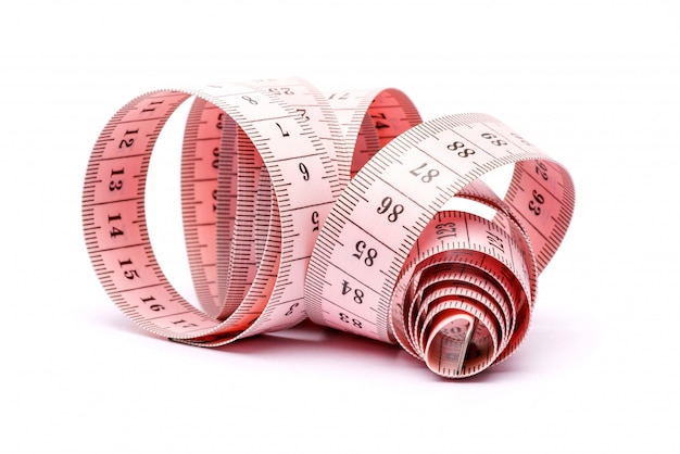 Unfolded white tape measure, White measuring tape isolated on pink  background. Close the tailor measuring tape on a pink background. The  concept of sports, diet, fitness, healthy eating. Copy space Stock Photo