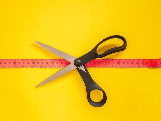 Pink measuring tape isolated on yellow 