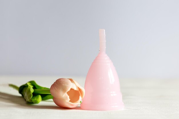 Pink menstrual cup lies on a white vintage wooden background