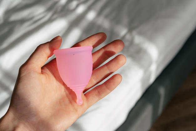 A pink menstrual cup lies in a woman39s hand Hygienic alternative to menstrual pads