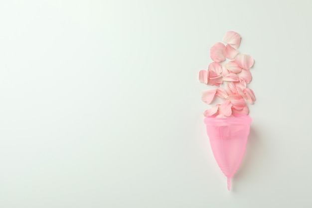 Pink menstrual cup with petals on white