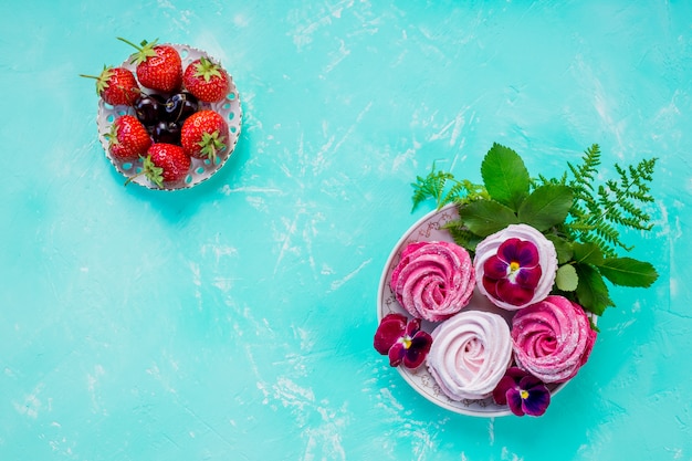 pink meringue cookies with berries for dessert