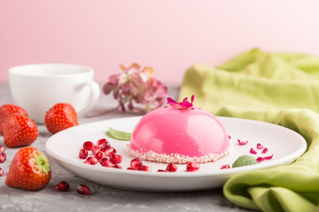 Pink mousse cake with strawberry  and a cup of coffee on a gray concrete surface. side view, selective focus.