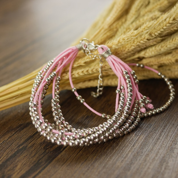 Розовый браслет из нескольких нитей на деревянном столе