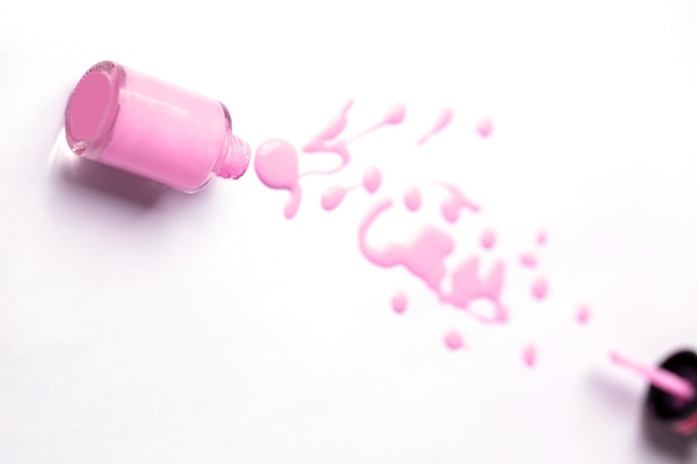 Pink nail polish bottle and drops on white background with copy space for text. Manicure, pedicure, cosmetics concept.