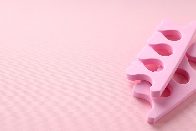 Pink nail separators on pink background, close up