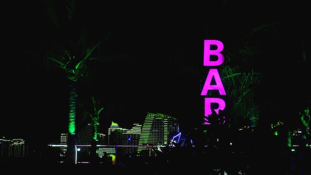 Foto insegna al neon rosa della parola bar su sfondo nero.