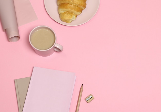 Nota rosa con matita e temperino, tazza di caffè, torta su sfondo rosa