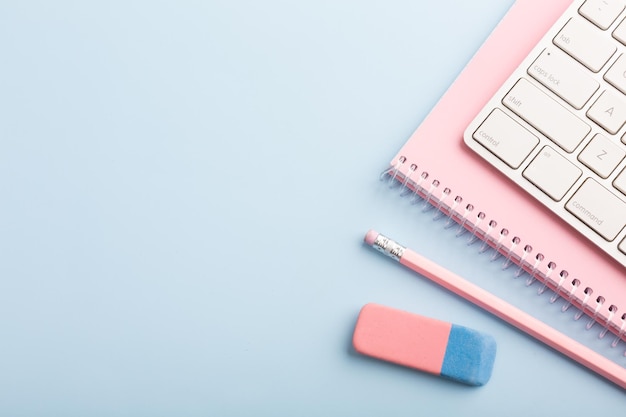 Pink notebook and pencil on a blue background Place for your text