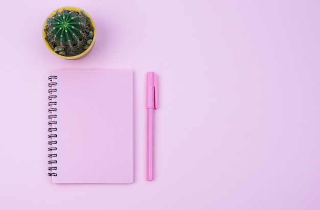 Pink notebook and pink pen on a pink background