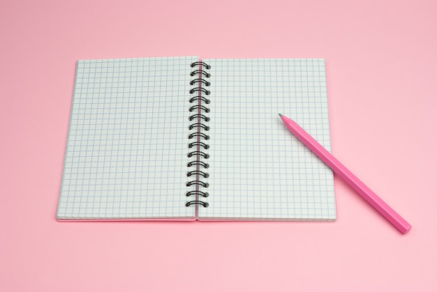 Quaderno rosa e penna rosa su sfondo rosa