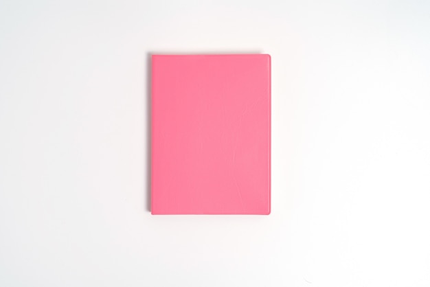 Photo pink notebook on white desk. business minimal concept for women. flat lay, top view, copy space