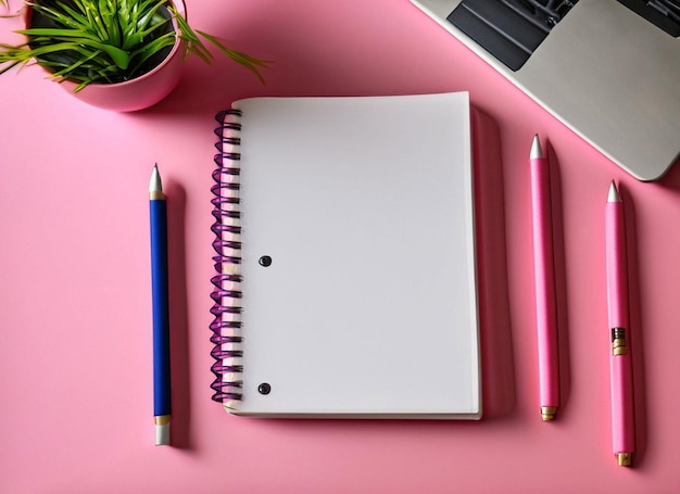 A pink notebook with a blue pen on it next to a laptop.