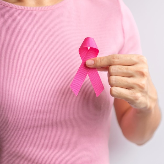 Pink October Breast Cancer Awareness month woman hand hold pink Ribbon and wear shirt for support people life and illness National cancer survivors month Mother and World cancer day concept