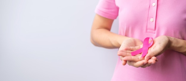 ピンクの10月の乳がん啓発月間女性の手はピンクのリボンを持ち、人々の生活と病気をサポートするためにシャツを着る
