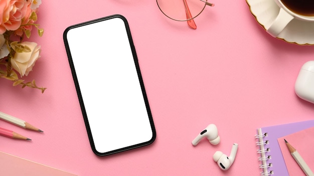 Photo pink office desk workspace with smartphone white screen mockup and office stuff top view flat lay