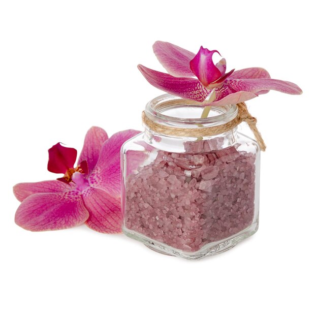白い背景に分離されたガラス瓶の中のピンクの蘭の花と入浴剤