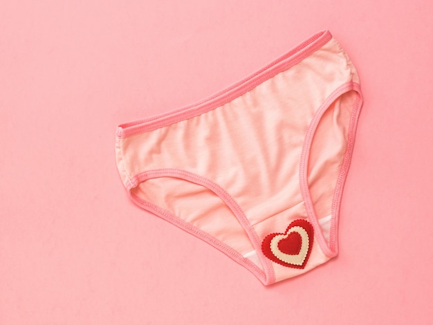 Pink panties with bright red heart on pink surface