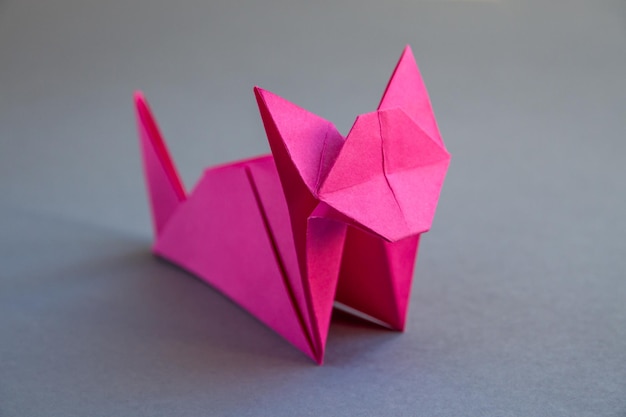 Origami di gatto di carta rosa isolato su sfondo grigio