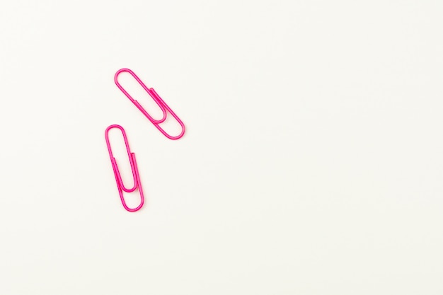 Pink paper clips on white background. 