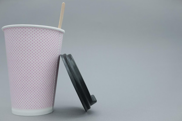 A pink paper cup, close-up, on a gray background.