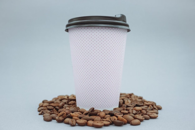 pink paper cup and plastic lid mockup or mockup, on gray background. scattered coffee beans.