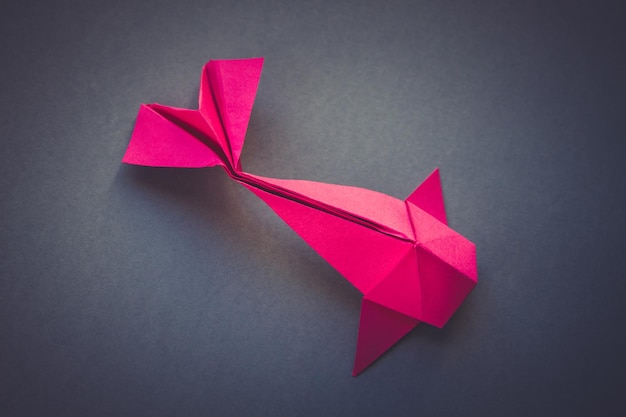 Origami di pesce di carta rosa isolato su sfondo grigio