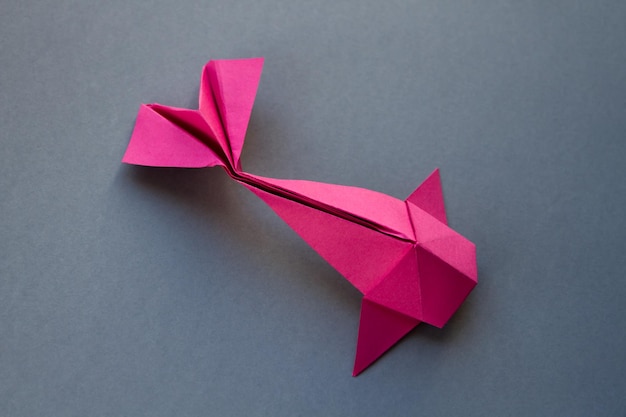 灰色の背景に分離されたピンクの紙の魚の折り紙