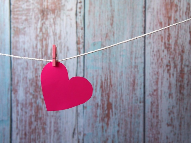 A pink paper heart is suspended from a clothesline