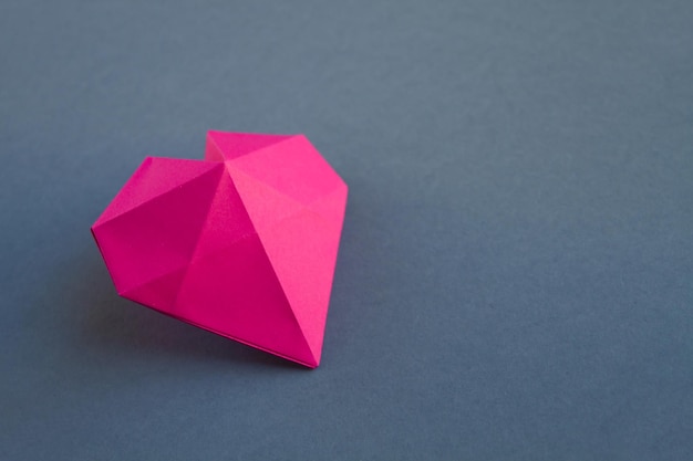 Pink paper heart origami isolated on a grey background