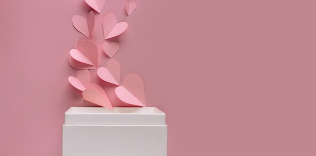 La forma del cuore di carta rosa viene espulsa dalla scatola bianca per festeggiare il giorno di san valentino per presentare l'amore