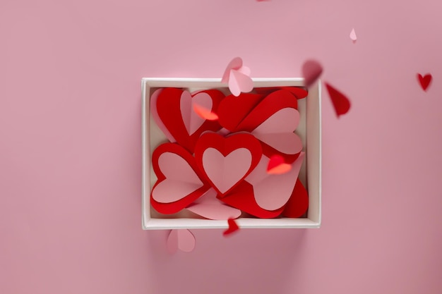 흰색 선물 상자에 분홍색 종이 하트 모양이 있고 발렌타인 데이에 위에서부터 현재까지 작은 종이 하트 드롭이 있습니다.