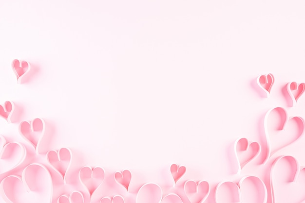 Pink paper hearts on pink paper background. Love and Valentine's day concept.