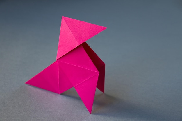 Foto origami di gallina di carta rosa isolato su sfondo grigio