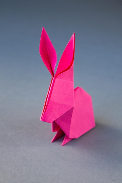 Pink paper rabbit origami isolated on a grey background