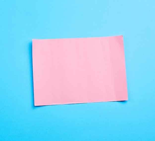 Photo pink paper sheet on blue surface