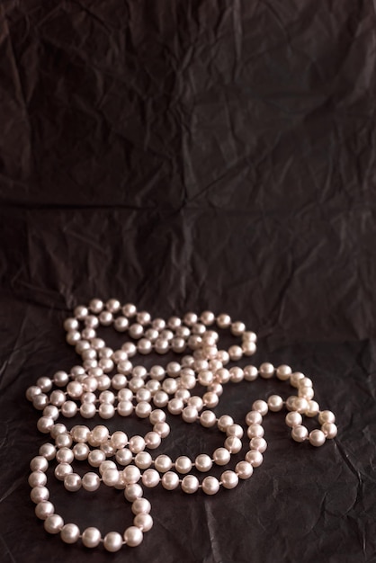 Pink pearls on black paper background with copy space
