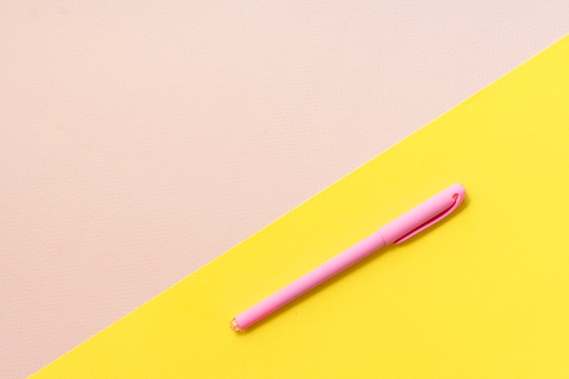 pink pen on yellow and beige, top view