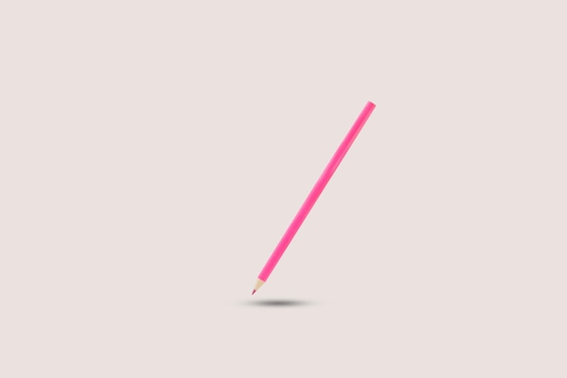 Розовый карандаш, плавающий на сером фоне с копией пространства