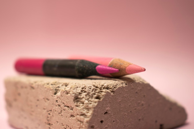 A pink pencil with a black tip sits on a concrete block.