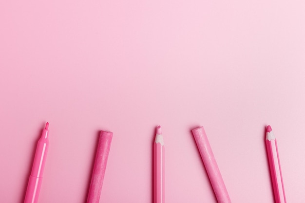 Photo pink pencils pastel crayons felttip pen on a pink background pink monochrome copy space top view