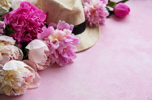 Pink peonies and hat on a pink concrete