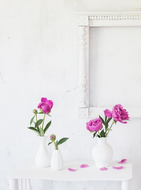 Pink peonies in vases on white background